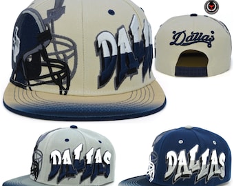 Op de afbeelding: Vier verschillende weergaven van een baseballcap met een Dallas Cowboys-thema. De pet is beige met blauwe en witte borduursels. De pet heeft een blauwe en witte gradiëntkleurige rand. De pet heeft een Dallas Cowboys-logo op de achterkant.