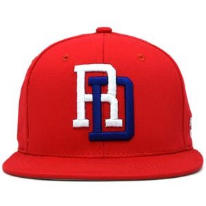 Puede incluir: Gorra de béisbol roja con visera plana. La gorra presenta un logotipo bordado en blanco y azul con las letras "RD". Esta gorra de estilo clásico es adecuada para ropa informal.