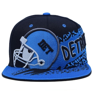 May include: A black and blue baseball cap with a flat peak. The cap features a blue football helmet graphic with the letters "DET" and the word "DETROIT" in white and blue. The cap is a fitted style.