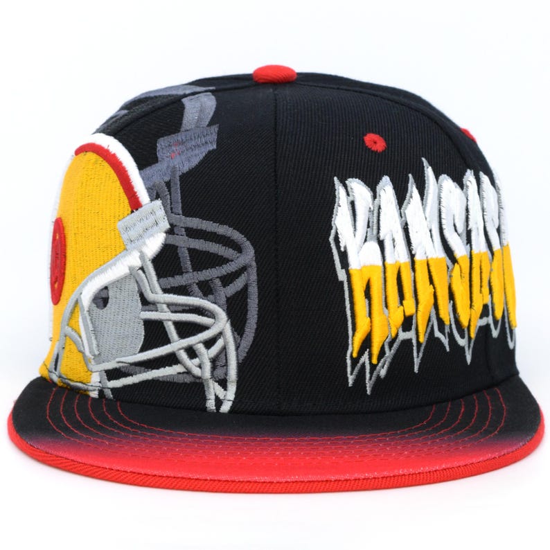 May include: Black and red fitted baseball cap with a yellow and white graphic of a football helmet and the text "Rams" in yellow and white.