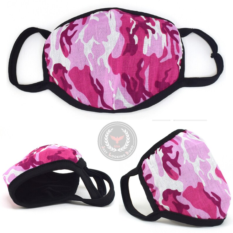 May include: Pink and white camouflage face mask with black elastic ear loops. The mask is made of a soft, breathable fabric.