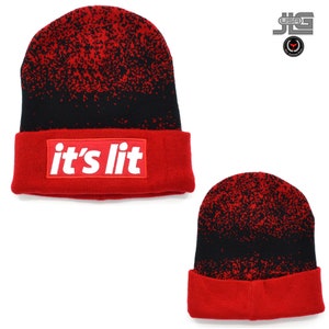 May include: Red and black knit beanie with a black and white speckled pattern. The beanie has a red fold-over cuff with a white patch that says "it's lit".