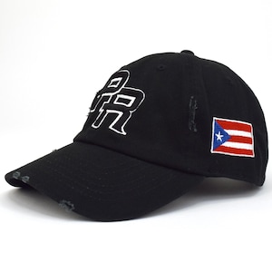 May include: Black baseball cap with white embroidered "PR" lettering on the front. The cap features a distressed brim and a small Puerto Rican flag patch on the side. The hat is made of a durable fabric.