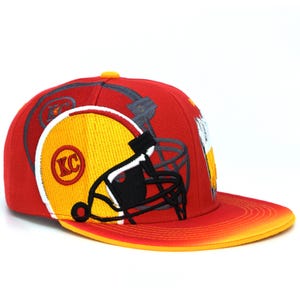 May include: Red and yellow baseball cap with a football helmet graphic and the letters "KC" on the front.