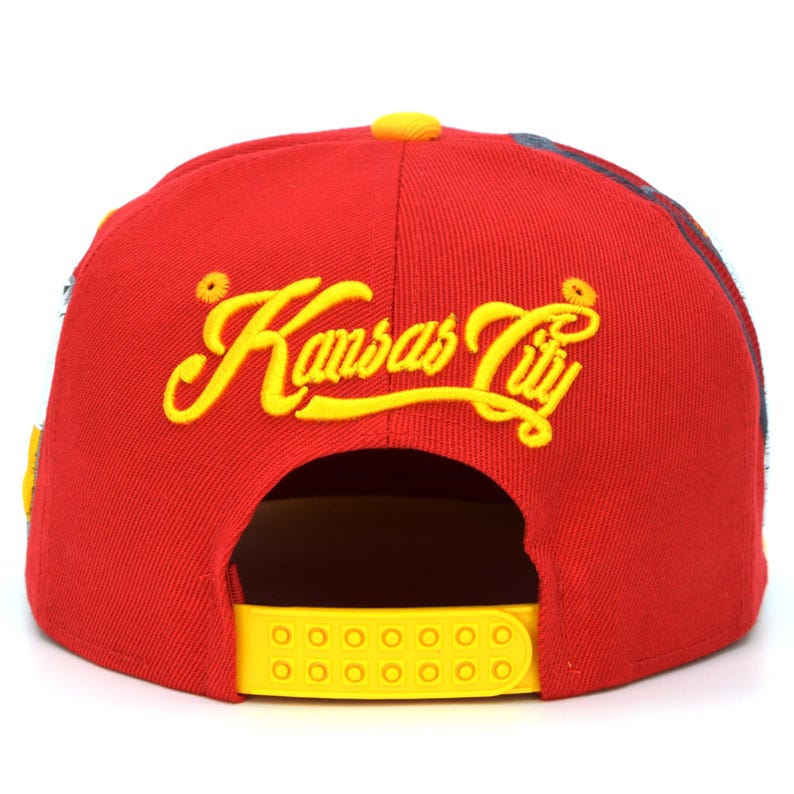 May include: Red baseball cap with a yellow adjustable strap and yellow embroidered text that reads "Kansas City".