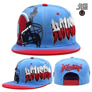 May include: Light blue baseball cap with a red brim and top button. The cap features the word "Houston" in white and red, along with a football helmet graphic. The back of the cap has the word "Houston" embroidered in red.