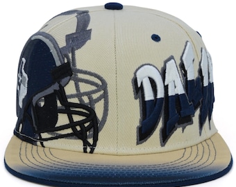 May include: A beige and navy blue baseball cap with a large embroidered graphic of a football helmet and the word "Dallas" on the front.