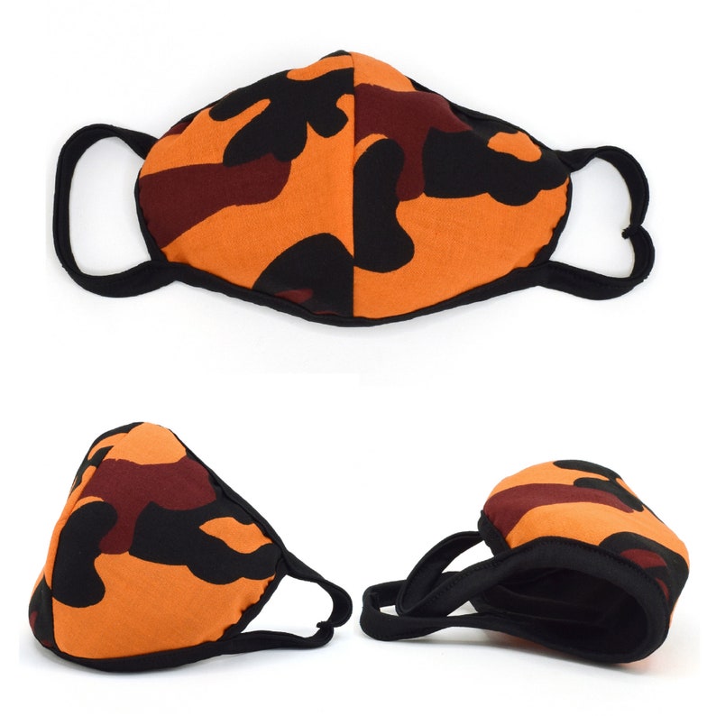 May include: A black, orange, and brown camouflage face mask with adjustable ear loops. The mask is made of a soft, breathable fabric.