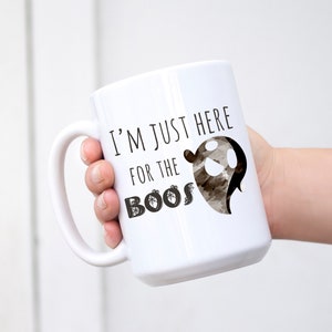 May include: White ceramic coffee mug with a black ghost graphic and the text "I'm just here for the boos".