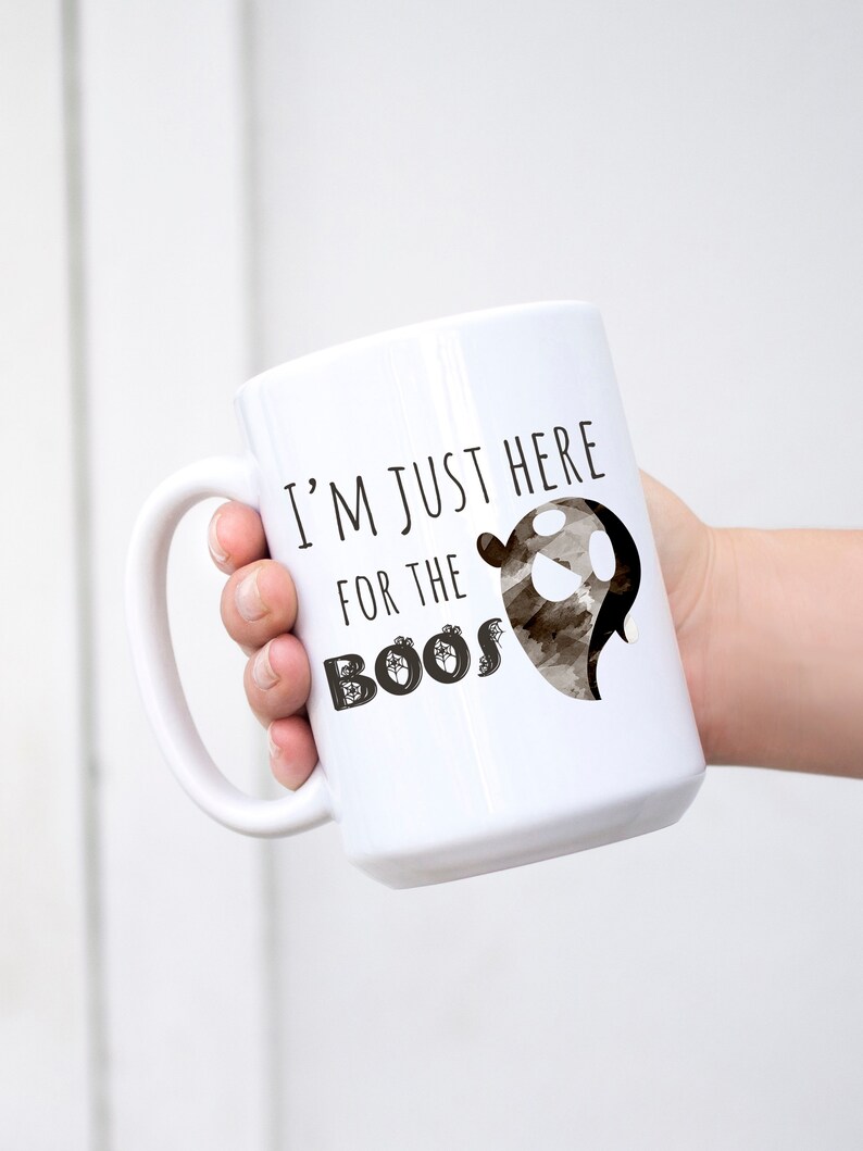 May include: White ceramic coffee mug with a black ghost graphic and the text "I'm just here for the boos".