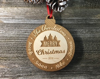 Könnte beinhalten: Ein Weihnachtsbaumschmuck aus Holz mit dem Text "The Charlestowns" und "Merry Christmas 2019" eingraviert. Der Schmuck enthält auch die Namen "Jacob, Susan, Mike und Anna" am Rand.