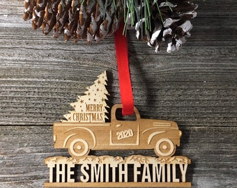 Könnte beinhalten: Weihnachtsbaumschmuck aus Holz in Form eines Pickups, der einen Weihnachtsbaum mit dem Text "Merry Christmas" und "2020" transportiert. Der Anhänger trägt außerdem den Text "The Smith Family" und "Anchor Gift Shoppe".