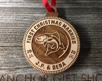 May include: A wooden Christmas bauble featuring a fish design and the text "First Christmas Married 2020 J.P. & Dera 2020".