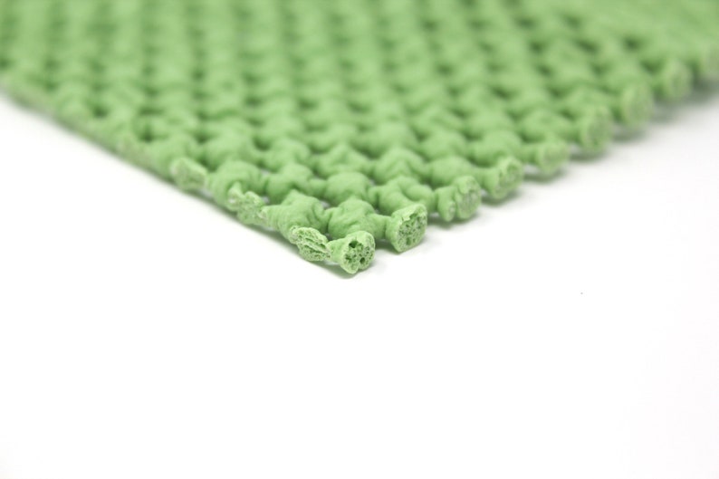 K&ouml;nnte beinhalten: Nahaufnahme einer gr&uuml;nen, strukturierten Gummimatte mit einem Gittermuster. Die Matte besteht aus kleinen, miteinander verbundenen Quadraten.