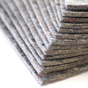 Puede incluir: Una pila de hojas de fieltro gris, cada hoja est&aacute; ligeramente desplazada de la que est&aacute; debajo, creando un efecto de capas.