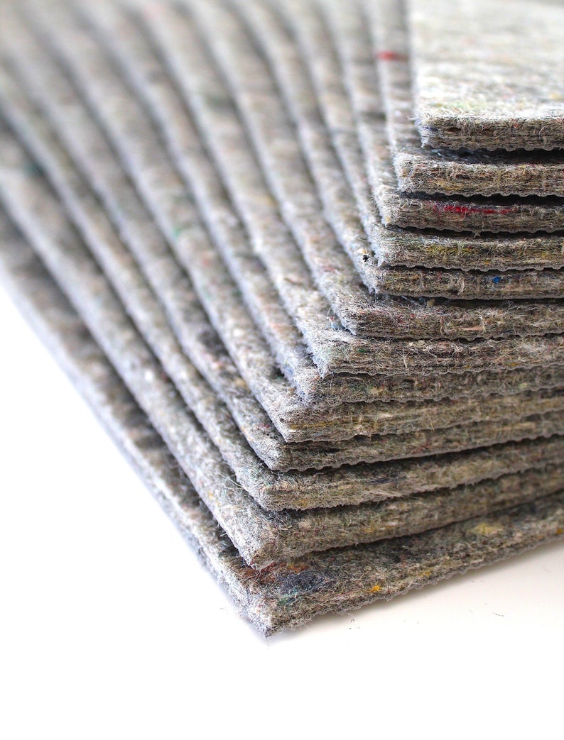 Puede incluir: Una pila de hojas de fieltro gris, cada hoja est&aacute; ligeramente desplazada de la que est&aacute; debajo, creando un efecto de capas.
