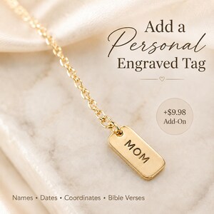 May include: A gold-toned metal chain featuring a small, rectangular engraved tag with the word MOM stamped in black capital letters. The text Add a Personal Engraved Tag, +$9.98 Add-On, and Names, Dates, Coordinates, Bible Verses are visible.