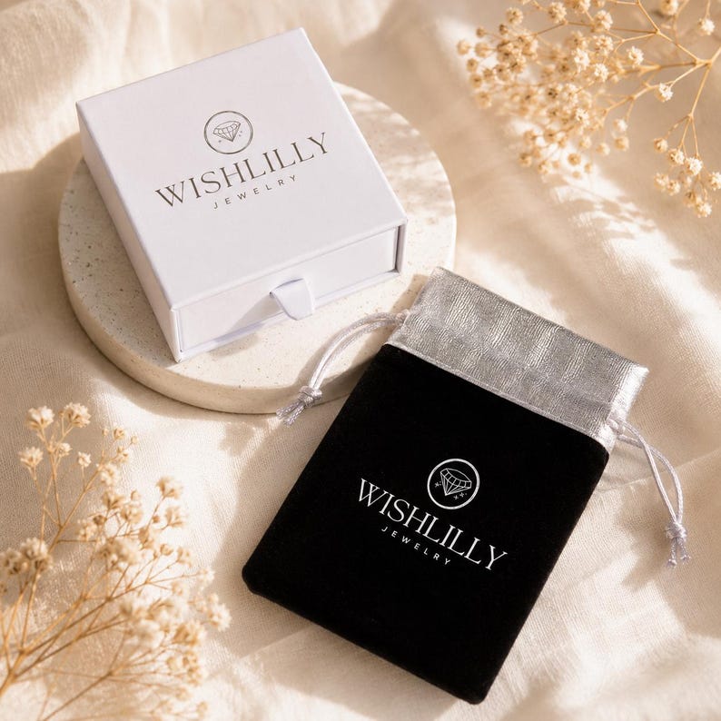 May include: A white square jewellery box with a pull-out drawer and the black text WISHLILLY JEWELLERY with a diamond icon, alongside a black velvet drawstring pouch featuring a silver top and the white text WISHLILLY JEWELLERY with a diamond icon.