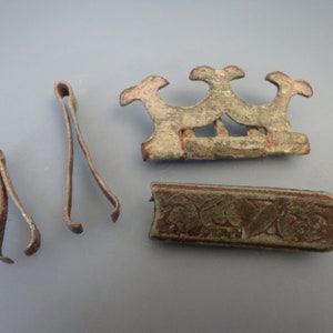 Puede incluir: Cuatro piezas de metal antiguas, que incluyen una pieza decorativa con tres cabezas de animales estilizadas, una pieza rectangular larga con un diseño grabado y dos piezas pequeñas y delgadas con extremos curvos.