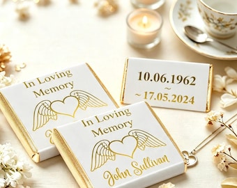 May include: Two white rectangular chocolate bars with gold foil edges, featuring the text In Loving Memory, a heart with wings, and the name John Sullivan. A third rectangular piece displays the dates 10.06.1962 and 17.05.2024 in gold lettering.
