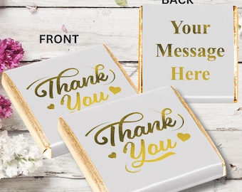 May include: Two white chocolate bars with gold foil wrappers. The front of the bar says "Thank You" in gold script with two small hearts. The back of the bar has a blank space for a personalized message.