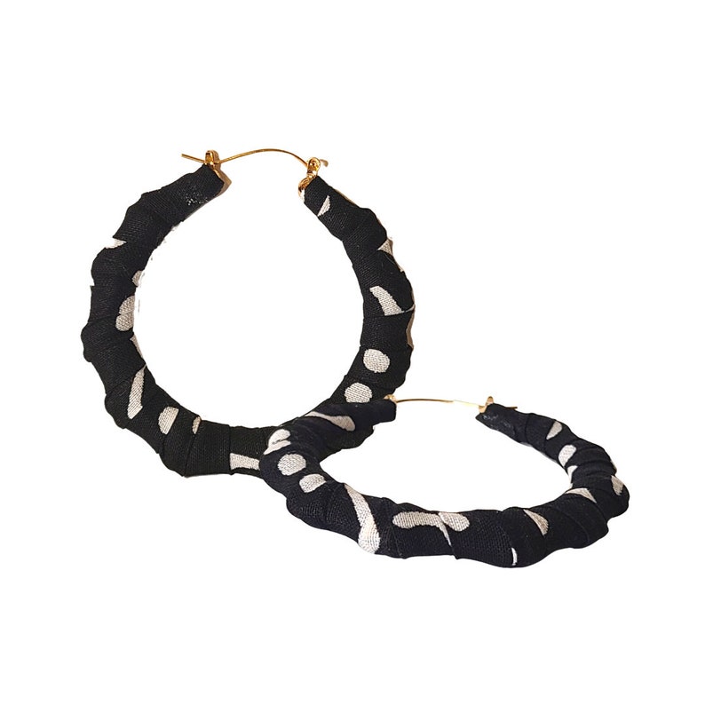 May include: A pair of large hoop earrings. The hoops are wrapped in black fabric with a white polka dot pattern. The earring posts are gold-colored.