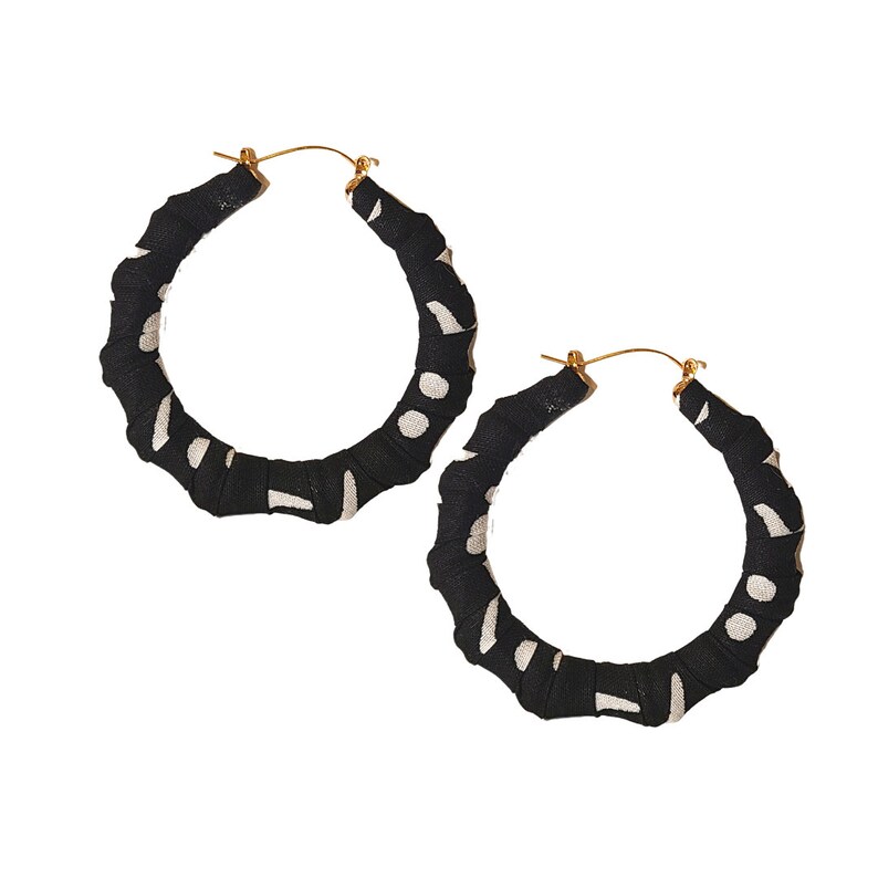 May include: A pair of large hoop earrings. The hoops are wrapped in black fabric with a white polka dot pattern. The earring posts are gold-colored.