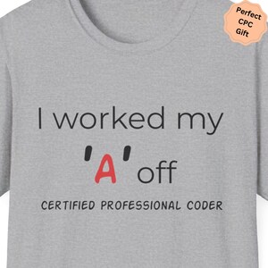 May include: A light grey t-shirt with the text "I worked my 'A' off" in black, with the letter "A" in red. Below the text is "CERTIFIED PROFESSIONAL CODER". A peach-coloured sticker in the upper right corner says "Perfect CPC Gift".