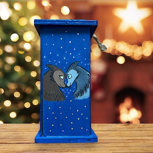 May include: A blue wooden box with a painted scene of two wolves facing each other. The wolves are painted in shades of brown and blue, and the background is a dark blue with white dots.
