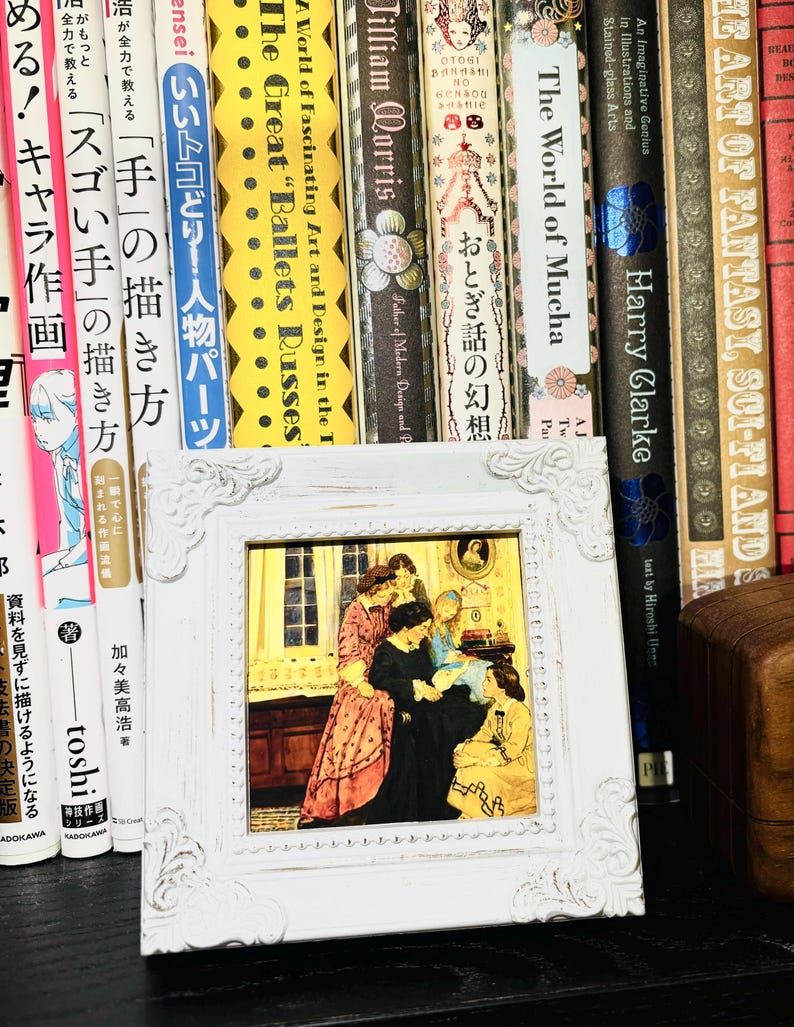 Puede incluir: Una imagen enmarcada en blanco con una ilustraci&oacute;n vintage de cuatro mujeres en una habitaci&oacute;n. Las mujeres llevan vestidos largos y est&aacute;n reunidas alrededor de una mesa. La imagen est&aacute; colocada en un estante con una fila de libros detr&aacute;s.