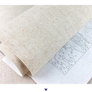 May include: A close-up of a beige canvas with a paint-by-numbers design printed on it. The design features a landscape with numbered sections for painting.