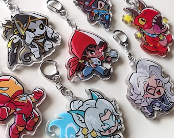 May include: A collection of seven acrylic keychains featuring various cartoon-style characters with vibrant colors, including a red dragon, a character in a red hood, a red and gold armored figure, and a white-haired figure with a blue tail.