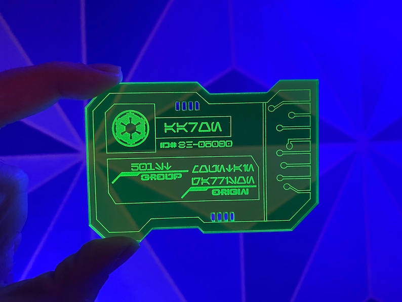Puede incluir: Una tarjeta de pl&aacute;stico verde con un s&iacute;mbolo imperial de Star Wars, el texto "KK70A", "ID# 3E-06090", "501st GROUP", "COLUMBIA", "DK771N0A" y "ORIGIN".