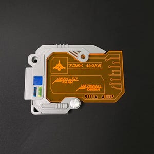 May include: A gray and orange plastic card with a circuit board design. The card has a small spaceship icon and the text "RANK 07" and "ORIGINAL" on it.