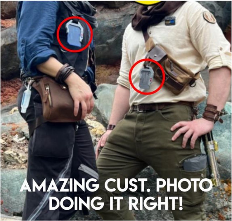 May include: Two people wearing brown leather belts with silver buckles and gray rectangular pouches attached to the belts. The pouches are attached to the belts with black straps. The people are wearing casual clothing. The text "AMAZING CUST. PHOTO DOING IT RIGHT!" is at the bottom of the image.