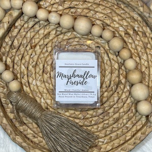 Puede incluir: Un derretido de cera blanco con el texto "Southern Grace Candle Marshmallow Fireside Wood | Vanilla | Amber Soy Blend Wax Melts | 2.8 oz | 79.3 g Hand-Poured in Texarkana, Texas" en la etiqueta. El derretido de cera est&aacute; sentado en una cesta tejida.