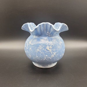 May include: A light blue ceramic vase with a ruffled rim and a white marbled design.