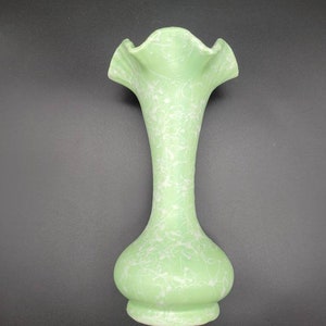 May include: A green ceramic vase with a white marbled design and a ruffled top.
