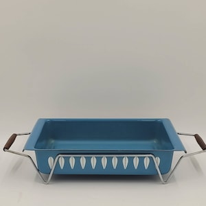 May include: A blue baking dish with a white leaf pattern sits on a metal stand with wooden handles.