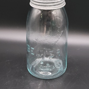 May include: A vintage blue glass jar with a silver metal lid. The word "BEAVER" is embossed on the front of the jar. The jar is empty and has a classic, rounded shape, ideal for preserving or storage.