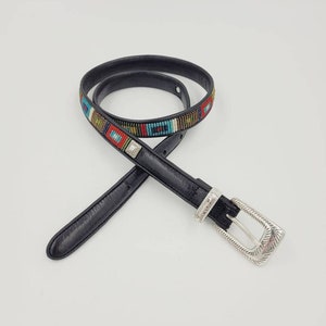 May include: A black leather belt with a silver buckle and colorful beaded design. The beads are arranged in a geometric pattern.
