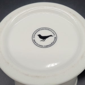 May include: White ceramic mug with a black bird logo that reads "Dishwasher & Microwave Safe. Made in China. Fabrique en Chine."