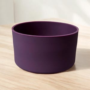 May include: A purple silicone cup coaster. The coaster is round and has a smooth surface.