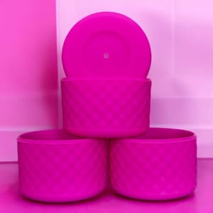 以下が含まれることがあります： ダイヤモンド柄のピンクのシリコン容器が3つ。容器は積み重ねられています。