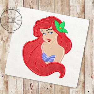 Pode incluir: Sereia de desenho animado de cabelo ruivo com uma flor verde no cabelo. Ela está usando um sutiã de concha de mar roxo e tem uma cauda vermelha.