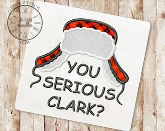Może przedstawiać: Haftowany wzór czerwono-czarnej czapki trapera z białym futerkiem i tekstem "You serious Clark?" w kolorze czarnym.