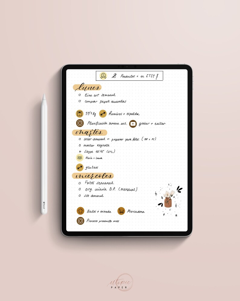May include: A digital tablet displaying a weekly planner with handwritten notes in Spanish. The planner includes daily tasks, weight tracking, and social media reminders. A white stylus rests beside the tablet on a pink surface. Text on the tablet reads "2 Productes en ETSY!"