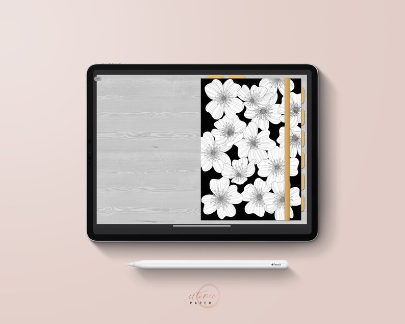 May include: A digital planner displayed on a tablet. The planner features a black background with white floral illustrations. A gold vertical tab and a light gray wood grain design are also visible. A white stylus and the text "utopic PAPER" are present.