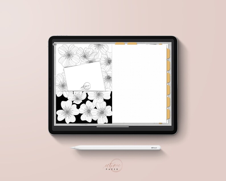 May include: A digital planner displayed on a tablet, featuring a floral design with black and white line art. The planner includes a card with the text "utopic paper" and a dotted grid layout. A white stylus rests below.