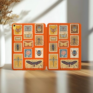 Puede incluir: Funda naranja para tableta con diseños de sellos postales vintage de insectos. Los sellos, en amarillo, azul y marrón, representan varios insectos. La funda está abierta, revelando el interior.